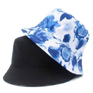 Detail view of cotton bucket hats in solid black and blue floral tie-dye patterns