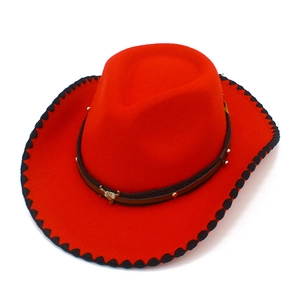 Detalle de sombrero vaquero rojo con logo de cabeza de toro y borde trenzado