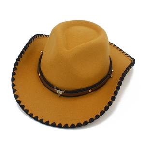 Detalle de sombrero vaquero amarillo con emblema de toro y borde trenzado negro