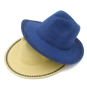 Detail view of woven straw sun hats in navy and beige showing fine fiber texture