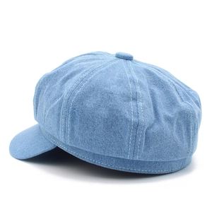 Detailed view of light blue denim newsboy cap with octagonal stitching and classic top button