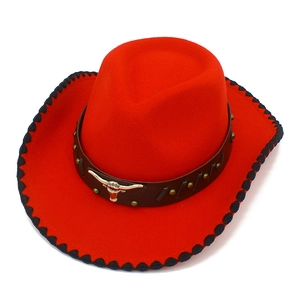 Detalle macro de sombrero vaquero rojo con banda de cuero, cabeza de toro y borde cosido negro