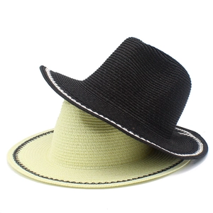 Detail of woven straw hats in black and beige with decorative contrast stitching