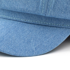 Close-up of vintage blue denim newsboy cap featuring detailed double-row stitching texture