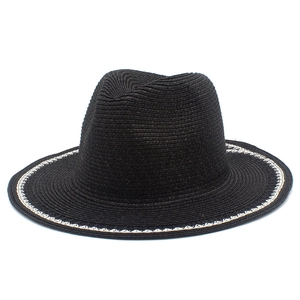 Detail of black woven straw sun hat with white wave pattern on the brim, summer chic style