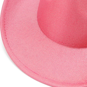 Macro detail of pink glitter fabric texture and reinforced stitching on cowboy hat brim