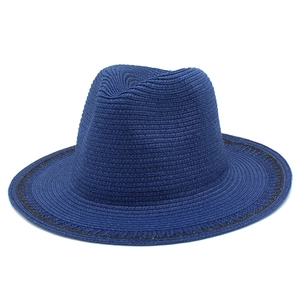 Detailed macro view of navy blue woven straw hat featuring classic black embroidered trim