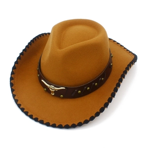 Detalle de sombrero vaquero con banda de cuero, emblema de cabeza de toro dorado y remaches