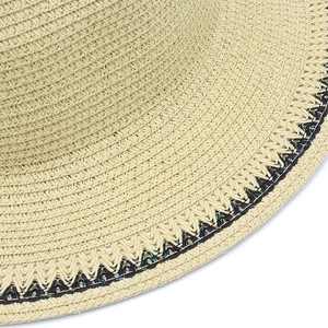 Detail of elegant straw hat showing tight weave texture and black wavy stitching accents