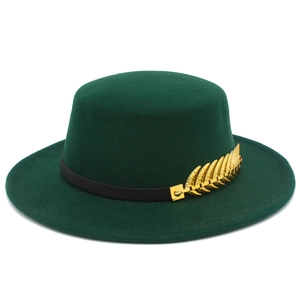 Close-up of dark green flat top wool hat with black ribbon and gold leaf ornament