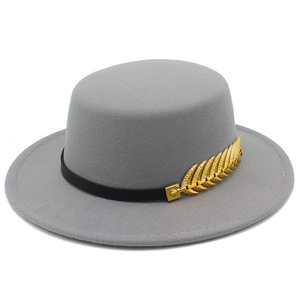 Close-up of a dark grey flat top fedora hat with a black leather band and golden leaf charm