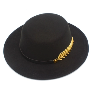 Detail of black boater hat with wool felt texture and golden metal leaf ornament