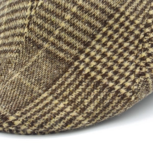 Close-up van bruin vintage houndstooth-patroon en stiksels op een wollen platte pet