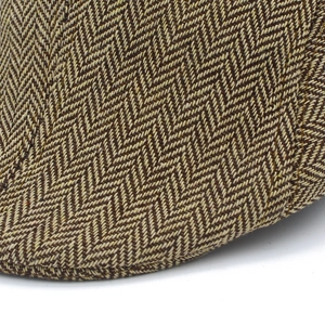 Detailopname van de bruine visgraat tweed stof en het nauwkeurige stiksel van de pet