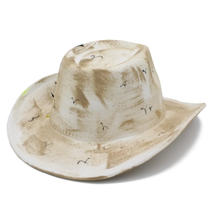 Detail of vintage cowboy hat with skull bird patterns and rustic distressed finish texture