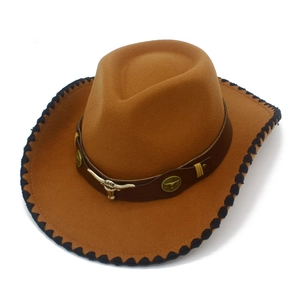 Detail of western cowboy hat featuring metallic bull head emblem and black stitched brim