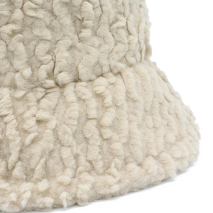 Close-up of beige lamb wool texture on a thick winter bucket hat showing soft fleece detail