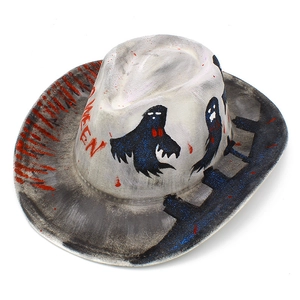 Detail view of a white Halloween cowboy hat featuring skull patterns and red blood splatters