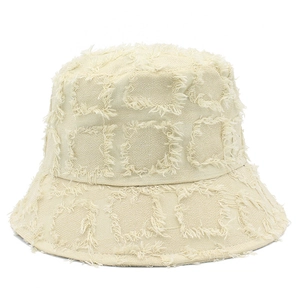 Dettaglio ravvicinato del cappello alla pescatora beige con bordi sfilacciati a quadri