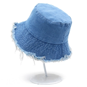 Chapeau bob en jean bleu clair avec bords effilochés sur un support minimaliste blanc