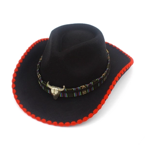 Macro shot of a black cowboy hat featuring red stitched edges and a bronze bull skull decor