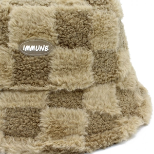 Detail of checkered lamb wool bucket hat featuring fluffy texture and sewn side label