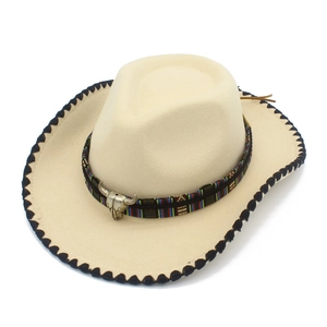Detail of beige cowboy hat featuring ethnic woven band and vintage bull skull charm