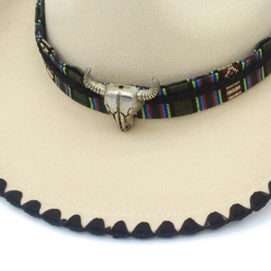 Close-up of western felt cowboy hat with ethnic woven band and metal bull skull ornament