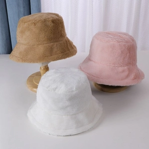 Detailed view of plush bucket hats in tan, pink, and white faux fur for winter warmth