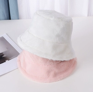 Detail view of plush bucket hats in white and pink showing soft faux fur texture