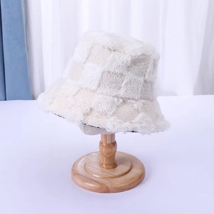 Detail shot of a plush checkerboard bucket hat in cream white on a wooden stand