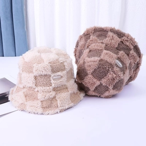 Close-up of fluffy checkerboard bucket hats in beige and brown faux fur texture