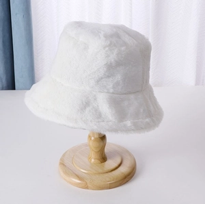 Detail view of white plush bucket hat on wooden stand for autumn and winter warmth