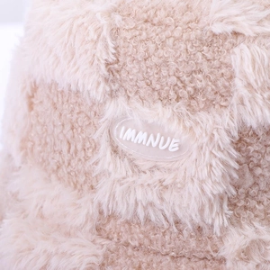 Close-up of checkered plush bucket hat showing soft faux rabbit fur texture and logo tag