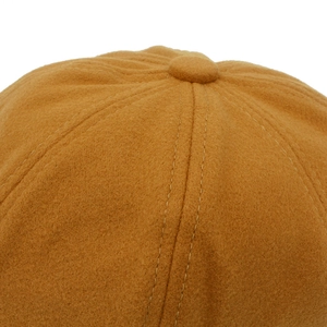Gros plan du sommet d'un béret jaune moutarde montrant les coutures et la matière