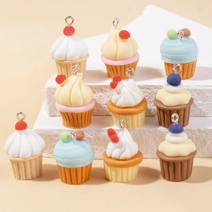 Colorful resin cupcake charms with cherry and sprinkles on stone display pedestal