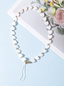 Vue détaillée de perles en cœur et de billes dorées sur une dragonne de téléphone