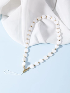 Détail du cordon de téléphone perlé avec coeurs blancs et billes dorées sur fond bleu