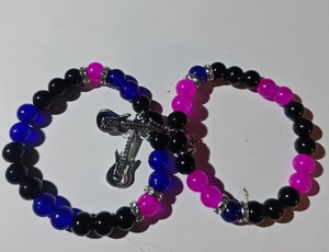 Detail of beaded couple bracelets with magnetic heart and silver guitar charms