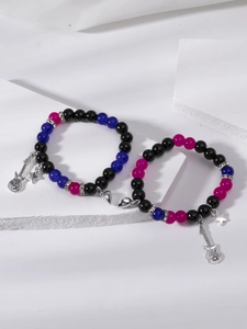 Macro detail of magnetic heart clasp with guitar charms on beaded couple bracelets