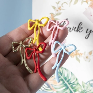 Colgantes de lazo de colores para joyería DIY, mostrados en la mano para ver el tamaño