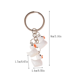 Sleutelhanger met drie witte hars eendjes en zilveren ring op een witte achtergrond