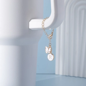 Detail of golden water cup chain featuring a white butterfly and letter R charm