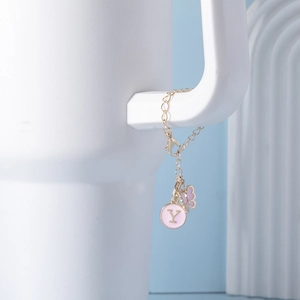 Detail of lobster clasp and gold chain with pink letter Y and butterfly pendant