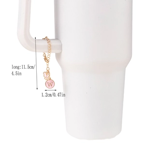 Detail of pink butterfly charm and enamel letter W pendant on golden cup chain with lobster clasp