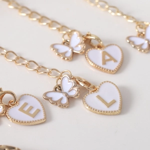 Macro view of gold alloy water bottle chains with white butterfly and letter pendants