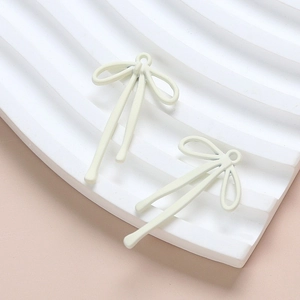 Macro shot of cream-colored bow charms with matte finish for DIY jewelry crafting