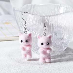 Pink flocked mini cat earrings with silver hooks shown on a decorative glass bowl