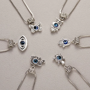 Set of six vintage silver evil eye necklaces featuring butterfly and hamsa hand pendants