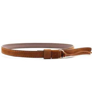 Détail de la ceinture en daim marron avec boucle dorée et décoration de longs glands